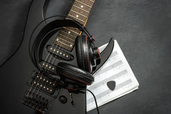 블랙 일렉트릭 기타와 헤드폰에 블랙 시멘트 바닥. — 스톡 사진