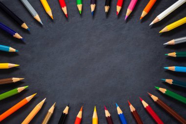 Kara tahta arka plan üzerinde renkli kalemler.