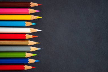 Kara tahta arka plan üzerinde renkli kalemler.