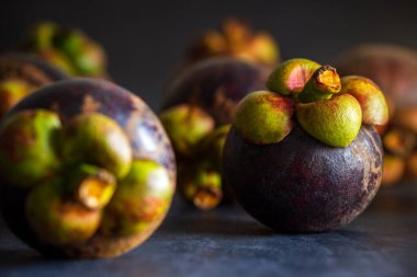 Siyah beton zeminde mangosteen meyvesi.