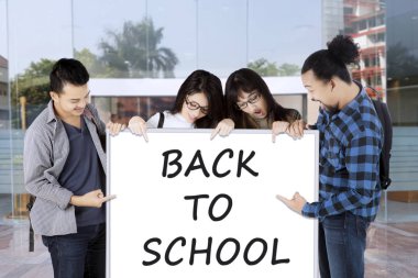 Beyaz tahta okula geri söyleyerek işaret eden üniversite öğrencilerinin grup