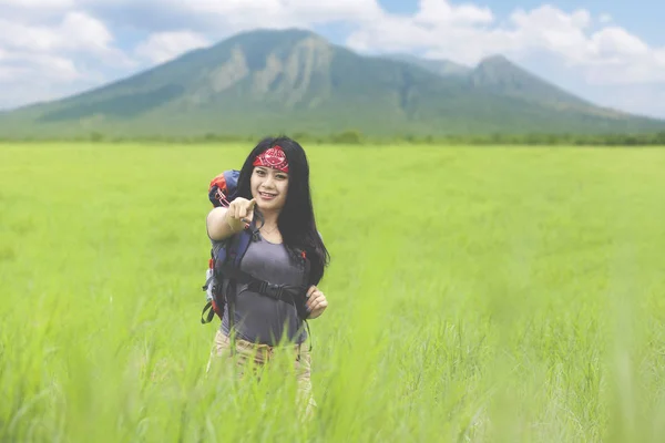 一个美丽的女人的肖像指向你 而站在草地上的山背景 — 图库照片