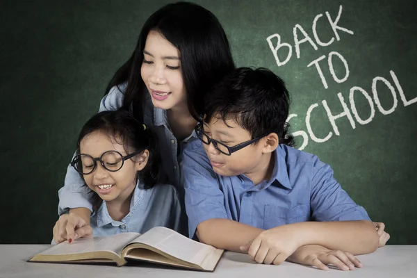 Imagen Una Bonita Maestra Ayudando Sus Estudiantes Leer Libro Mientras — Foto de Stock