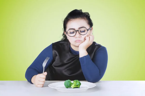 在盘子里看花椰菜时拿着叉子的胖女人肖像 — 图库照片