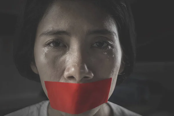 彼女の口は赤いテープで覆われて暗い部屋で泣いている虐待を受ける女性のイメージ — ストック写真