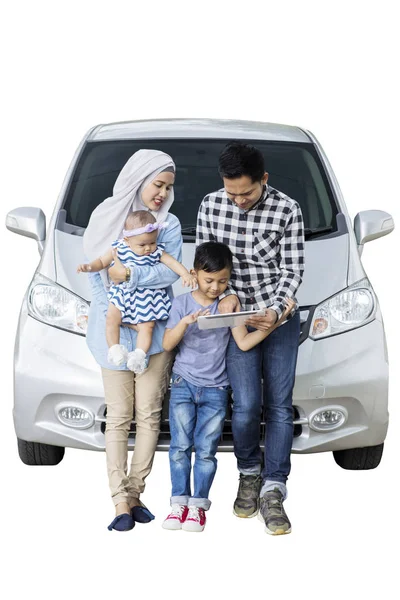 デジタル タブレット 白い背景で隔離を押しながら自分の車の前に座っているイスラム教徒の家族の肖像画 — ストック写真