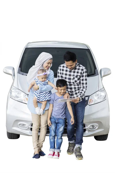 Portrait of Muslim family leaning on the hood of their car while using a tablet, isolated on white background