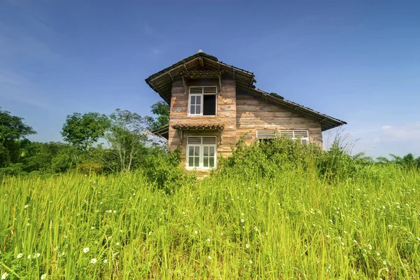 Mavi gökyüzünün altında bozuk pencere ile terk edilmiş ahşap evin resmini