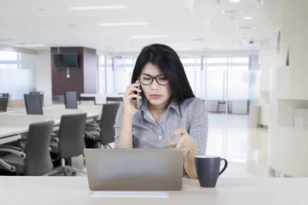 亚洲女商人在电话中要求帮助修复她的笔记本电脑损坏 而坐在办公室 — 图库照片