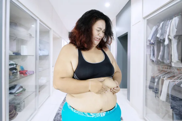 肥胖妇女的图片在捏她的腹部肥胖和站立在更衣室里看起来哭泣 — 图库照片
