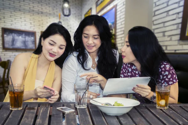 三位女士在聊天和坐在咖啡馆时使用平板电脑和智能手机的图片 — 图库照片