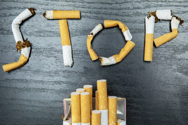 Bir Kelime Closeup Dur Sigara Izmaritleri Tablosunun Üstünde Bir Sigara — Stok fotoğraf