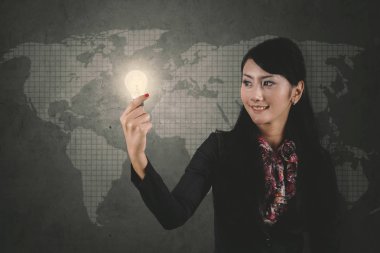Kadın girişimci duran dünya harita arka plan ile parlak bir ampul holding resmi