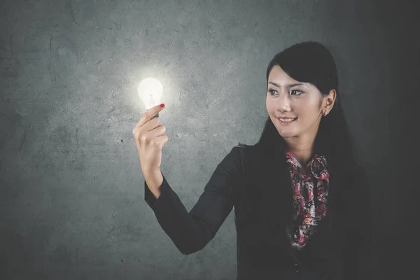 一个美丽的女商人的图片 当持有一个明亮的灯泡思考一个想法 — 图库照片