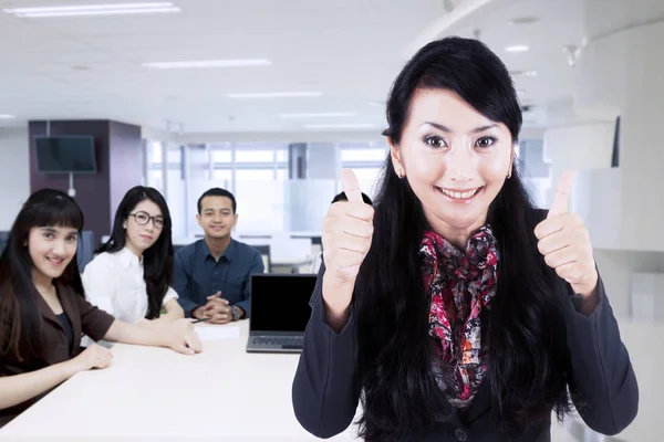 女性ビジネス リーダーのオフィスで彼女のチームに立っている間に親指を表示 — ストック写真