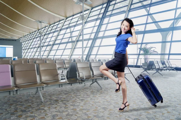 漂亮的女商人的图片看起来很高兴 而拉着一个手提箱 站在机场候机楼 — 图库照片