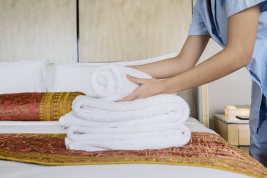 Genç kadın hizmetçi closeup beyaz banyo havlu çarşaf üzerine bolca toplama eller