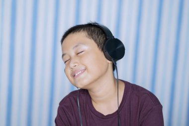 Portre sevimli küçük çocuk yatak odasında otururken smartphone kullanarak müzik keyfi