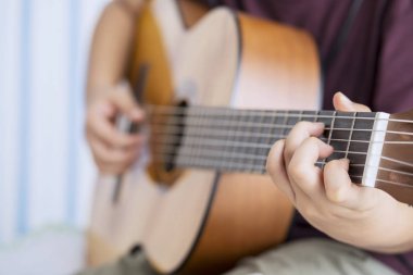 Bilinmeyen küçük çocuk elleri bir akustik gitar tıngırdatmaya için pratik, yakın çekim