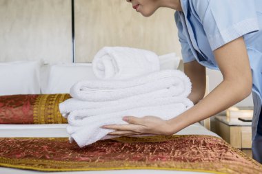 Bir yığın beyaz banyo havlu çarşaf üzerinde koyarak bilinmeyen kadın hizmetçi resmini