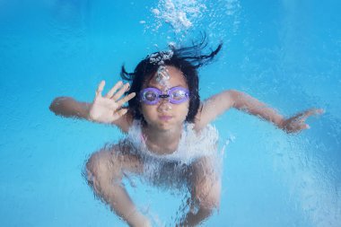 Sevimli küçük kız resmi sualtı yüzme havuzunda yüzme sırasında mutlu görünüyor 