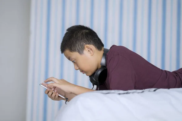 Zijaanzicht Van Aziatische Jongetje Met Behulp Van Een Smartphone Liggend — Stockfoto