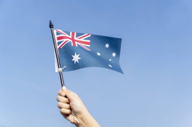 Arka plan mavi gökyüzü ile bir Avustralya bayrağı sallayarak bilinmeyen çocuk el yakın çekim