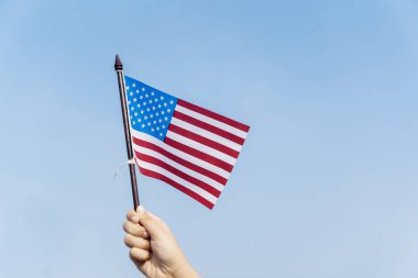 Bir Amerikan bayrağı mavi gökyüzü altında sallayarak süre tutarak bilinmeyen çocuk el yakın çekim