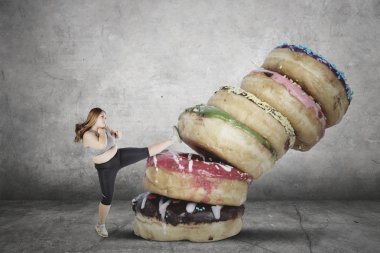 Bir yığın Donuts tekmeleme tarafından tatlı yemek reddederek ise spor giyim giymiş obez kadın portresi