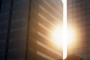 İki yüksek binalar yarık parlayan güneş ışığı resmi. Gün batımı anda vurdu