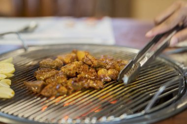 Sığır eti dilim soba kömür ızgara maşa kullanarak bilinmeyen kadın el yakın çekim