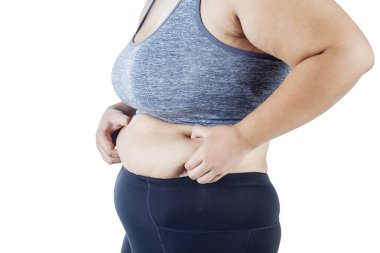 Spor giyim, beyaz arka plan üzerinde izole giyerken şişman karnı sıkma obez kadın closeup eller