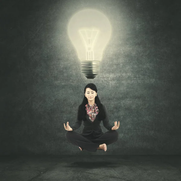 Young Businesswoman Doing Meditation While Levitating Bright Bulb — Stock Photo, Image