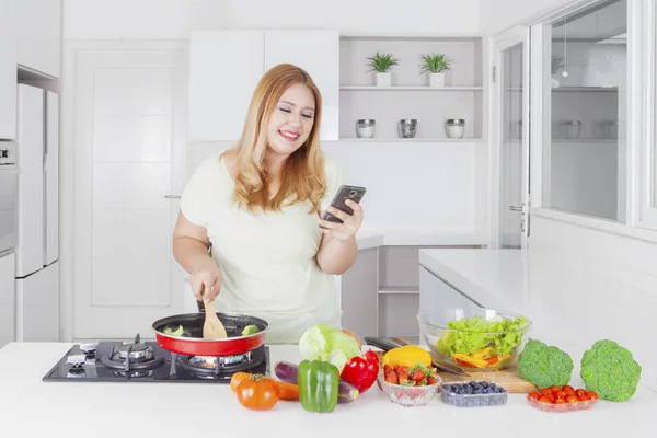 Foto Una Mujer Caucásica Obesa Usando Teléfono Inteligente Cocinando Verduras — Foto de Stock