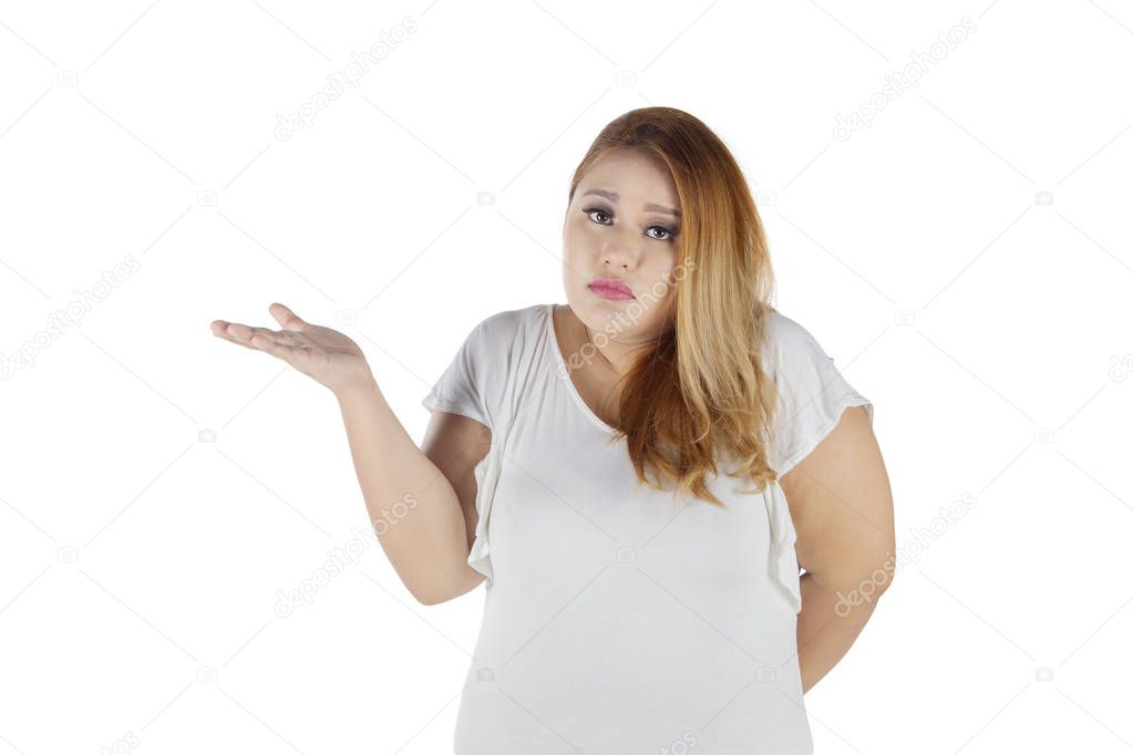 Picture of Caucasian fat woman looks confused while standing in the studio, isolated on white background