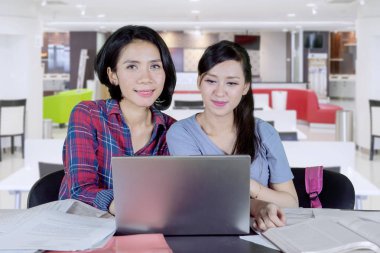 Kafede onun arkadaşı ile birlikte okurken bir dizüstü bilgisayar kullanarak Asya Kolej Öğrenci