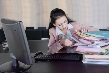Beyaz iş kadını ofiste otururken bir bilgisayar ve belgeleri yığını çalışma görüntü