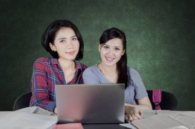 Beyaz kız arkadaşı sınıfta birlikte okurken kameraya gülümseyen