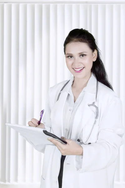 Obraz Piękna Doktor Uśmiechając Się Kamery Podczas Pracy Schowka Klinice — Zdjęcie stockowe