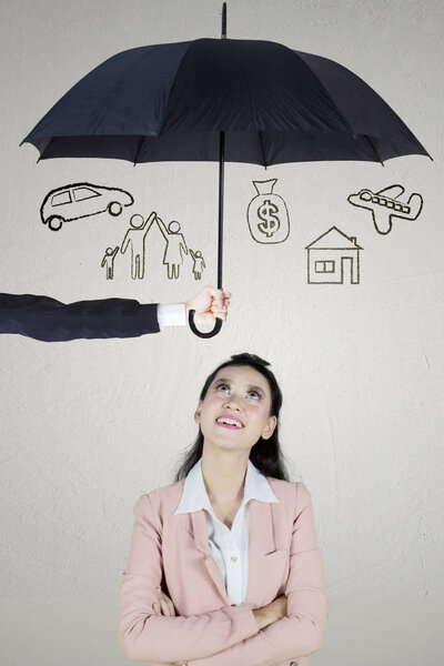 Portrait of pretty entrepreneur thinking her dreams while standing under an umbrella. Concept of dreams insured