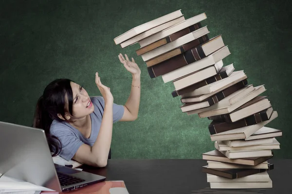 女大学生形象在捧着一堆掉落的书和坐在教室里时显得很疲倦 — 图库照片