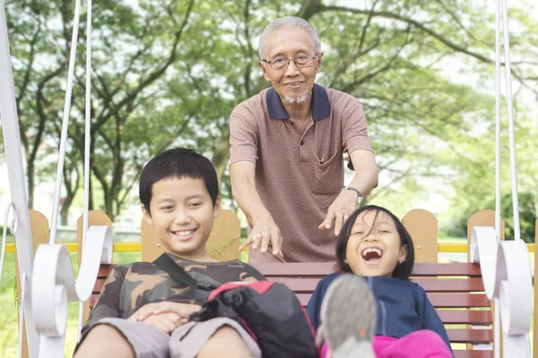 Yaşlı Adam Onun Torunları Birlikte Parkta Oynarken Salıncak Iterek Resmi — Stok fotoğraf