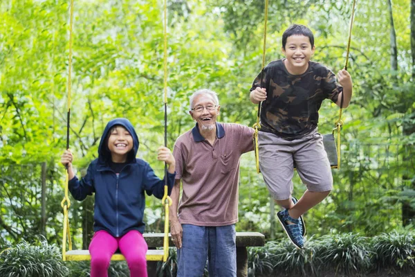 Imagen Del Anciano Feliz Con Sus Nietos Jugando Con Columpios —  Fotos de Stock