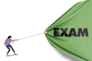Picture of a beautiful girl struggling to pull a green banner with exam word, isolated on white background clipart