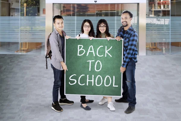 Group of college students holding a green board saying Back to school