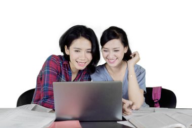 İki mutlu kadın üniversite öğrencileri bir dizüstü bilgisayar kullanarak ve birlikte, eğitim izole beyaz arka plan üzerinde