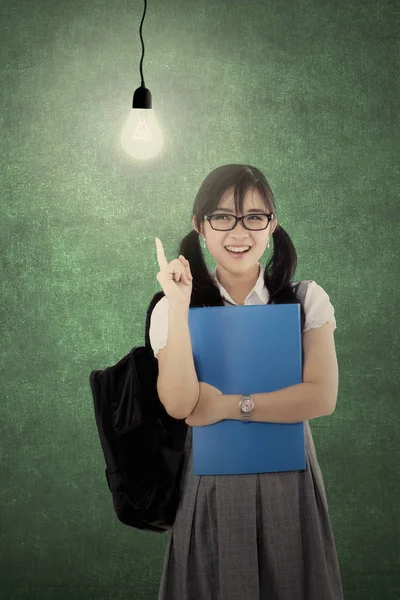教室で電球の下に立っている間アイデアを得るかなりの高校生の肖像画 — ストック写真