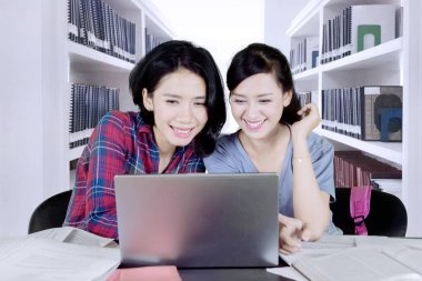 Bir dizüstü bilgisayar kullanarak ve arkadaşı kütüphanede ödev beyaz kız resim