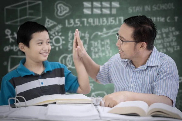 Picture of male teacher giving high five to his student while studying together in the classroom