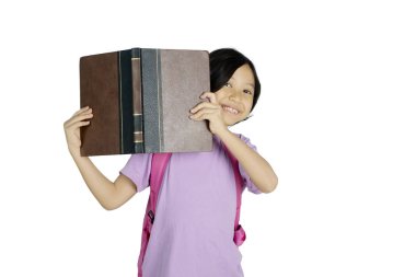 Küçük kızın bir kitap ise kameraya gülümseyen ve beyaz arka plan üzerinde izole stüdyoda ayakta tutan 